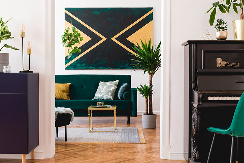 House interior with emerald green and dark grey accents, lots of potted plants with view into living room with emerald green velvet couch